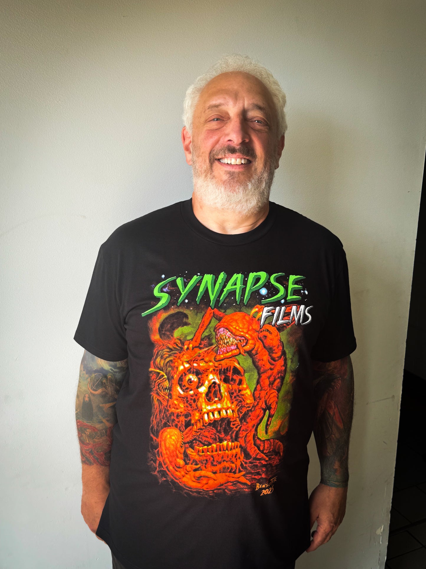 Man wearing a black t-shirt with 'Synapse Films' design against a plain background